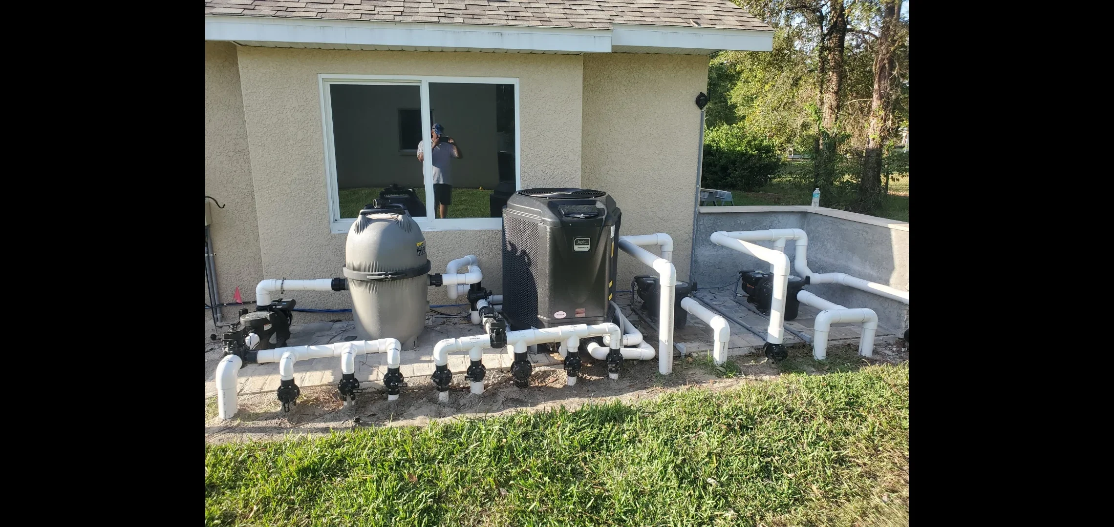 Sand filter, heat pump, and white PVC plumbing system installed on pool deck