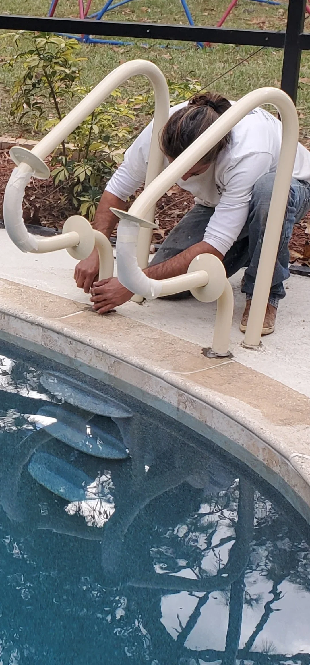 White PVC curved handrails installed on pool deck with secure mounting flanges