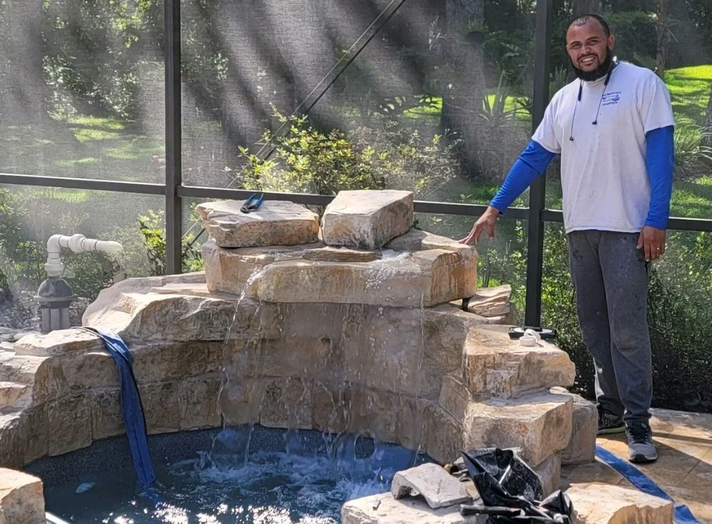 Stacked natural stone waterfall feature with blue water circulation and pool basin