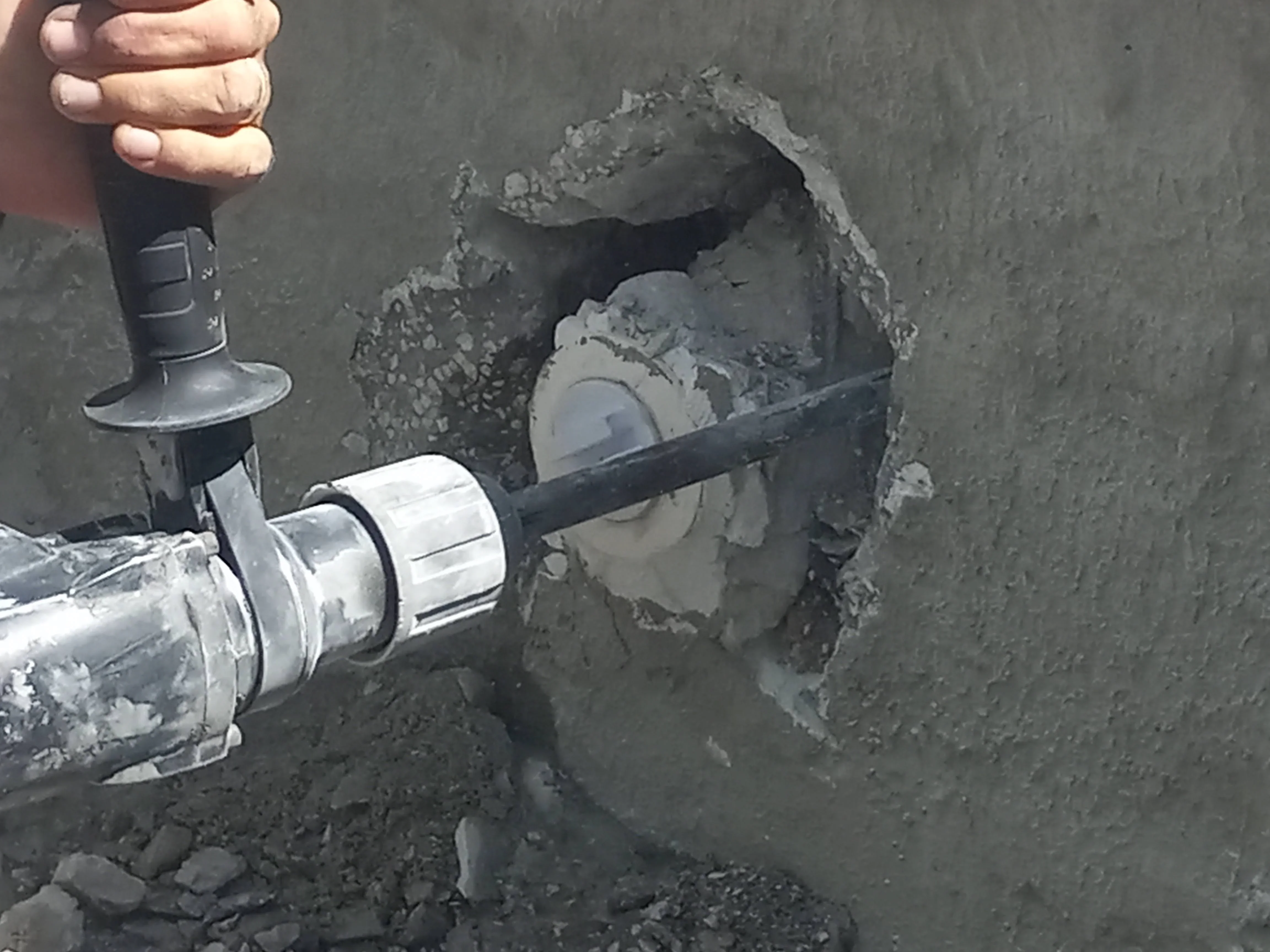 PVC pool plumbing connection with white fittings installed in concrete pool wall